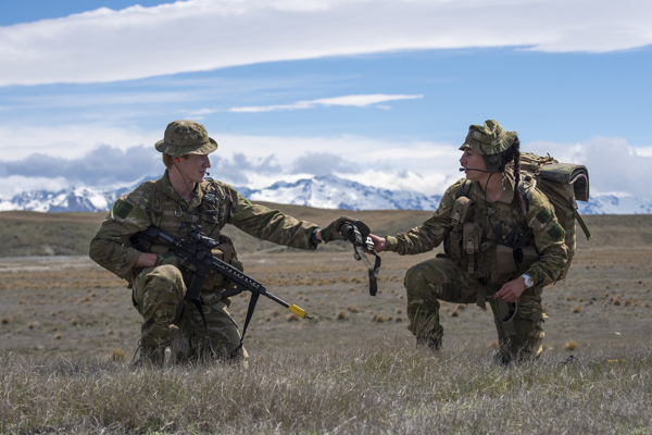 Two NZDF soldiers training in open terrain with mountains in the background